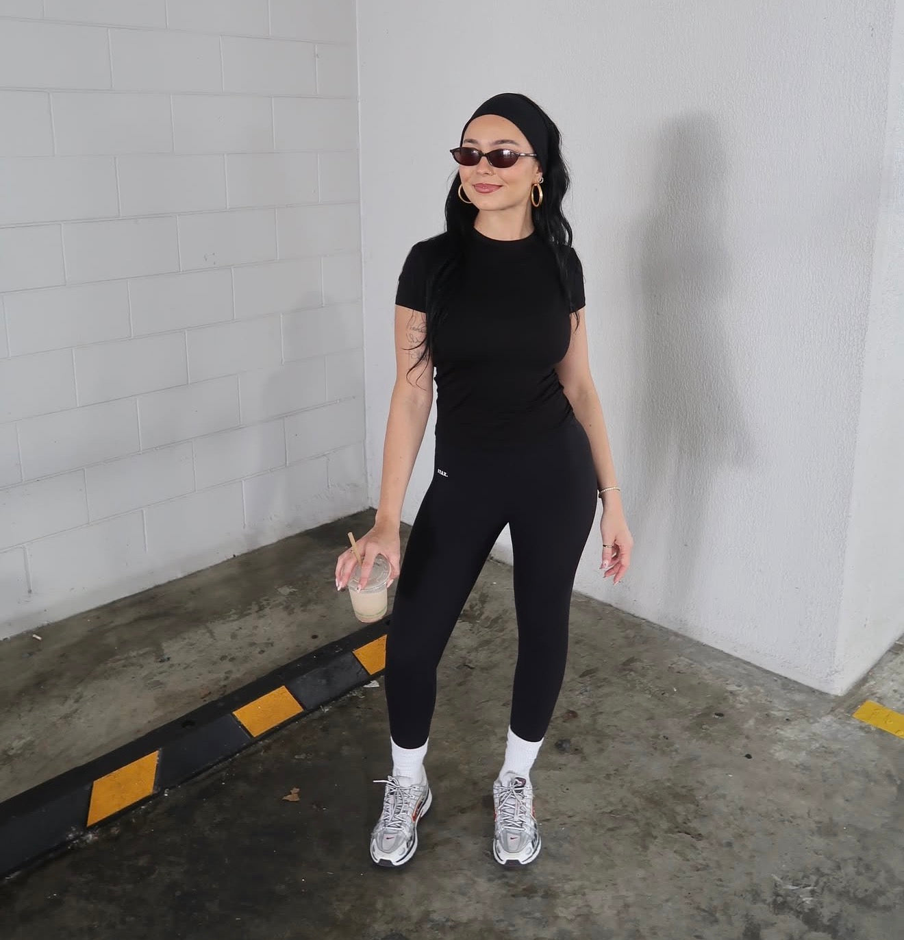 Person wearing a black outfit holding a drink in an indoor setting