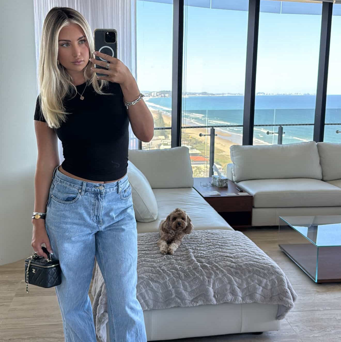 Woman taking a mirror selfie in a modern living room with ocean view
