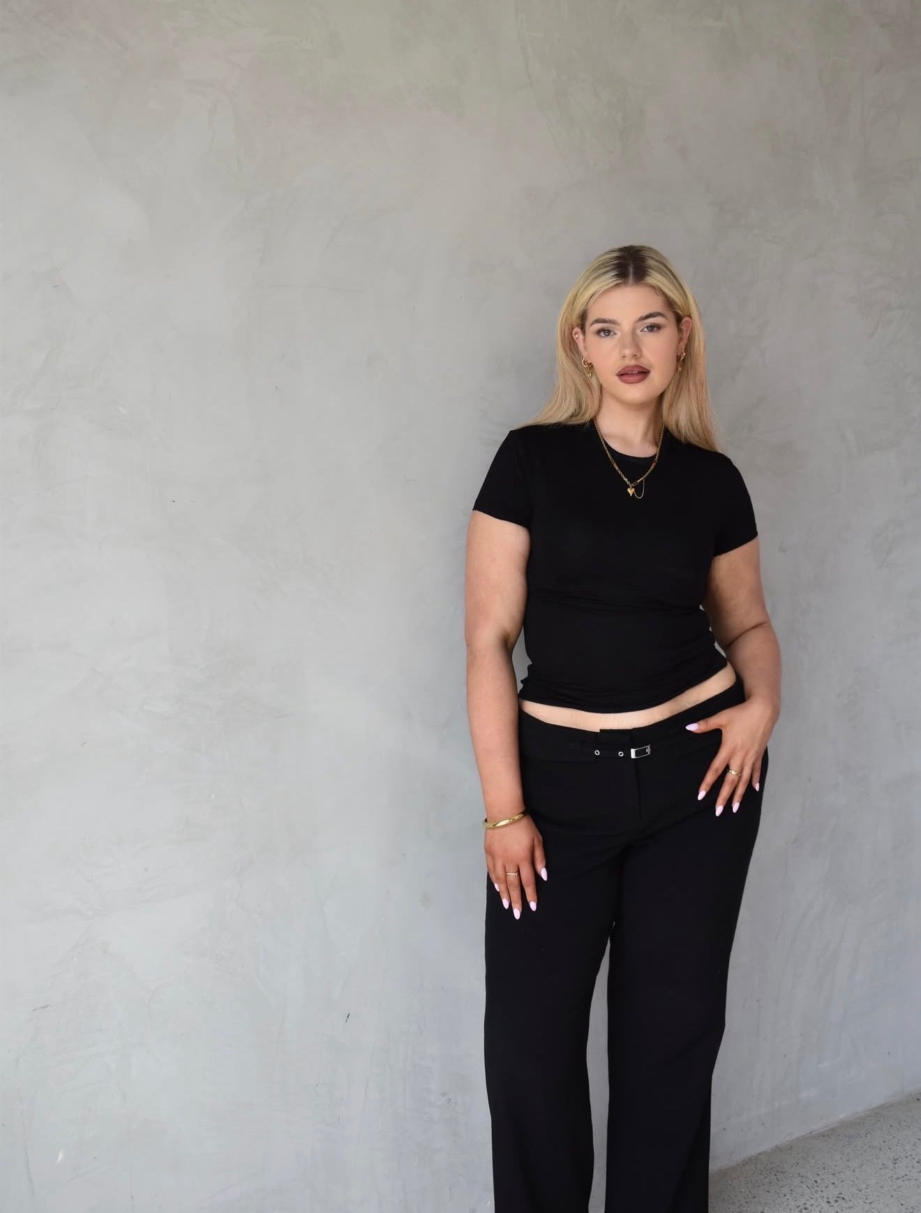 Woman wearing a black outfit against a gray background